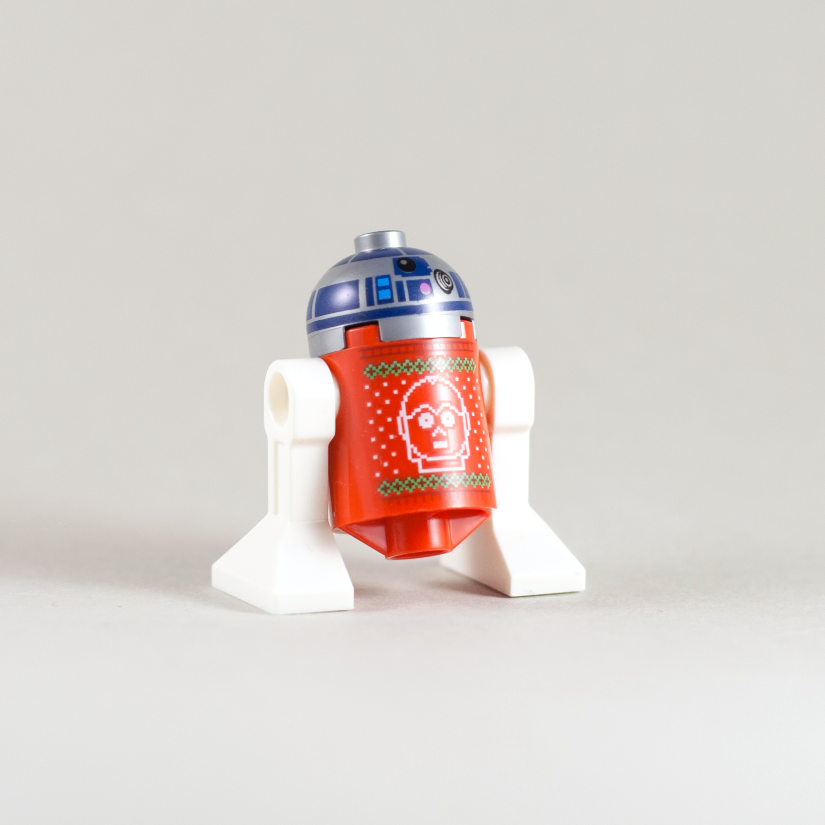 LEGO R2-D2 v prelepem rdečem božičnem puloverju na katerem je spleten obraz C-3PO